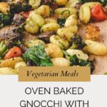 A close-up of oven baked gnocchi mixed with pesto, broccoli, and vegetables on a sheet pan, with a wooden spoon. Text reads: Vegetarian Meals. Oven Baked Gnocchi with Pesto. Whensaltyandsweetunite.com.