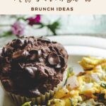 A gluten-free chocolate chip muffin with hazelnuts sits beside scrambled eggs with vegetables. Text above reads, “Gluten Free Chocolate Chocolate Chip Muffins with Hazelnuts – Brunch Ideas.”.