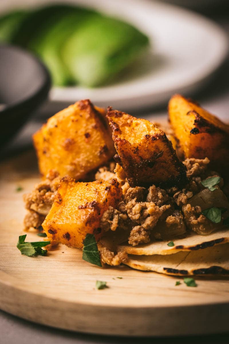 close up picture of the butternut squash taco on a plate and tortillas