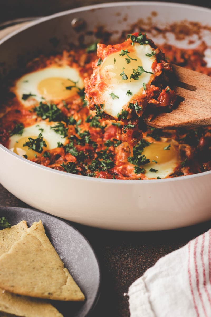 serving shakshuka with a wooden spatula