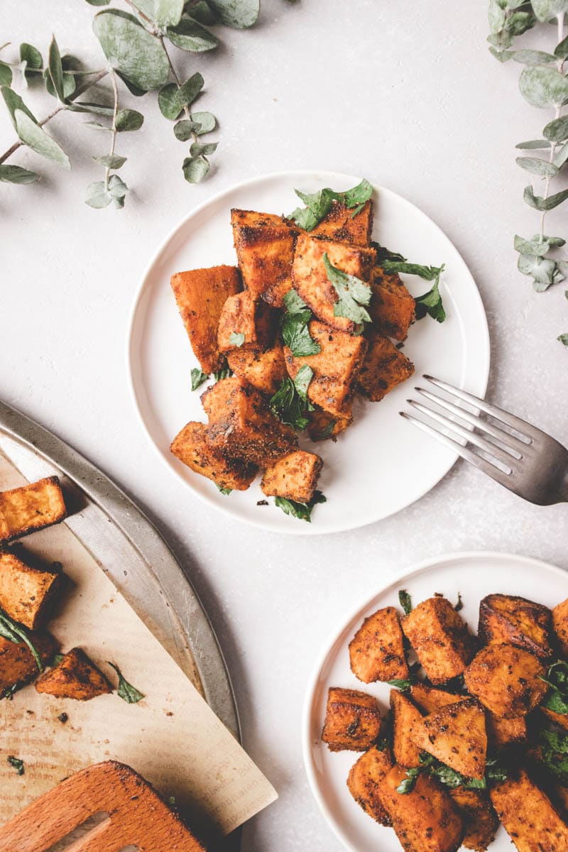 2 plates of cumin roasted sweet potatoes on white plates.