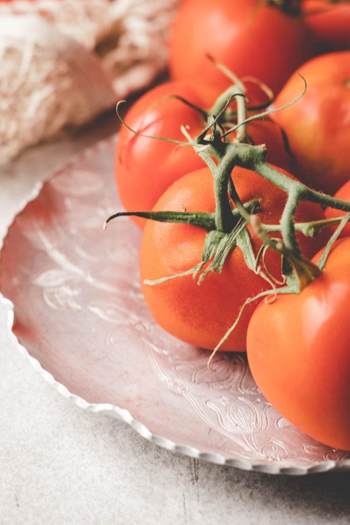 comparing camera settings -tomatoes on the vine , sitting on a vintage plate 