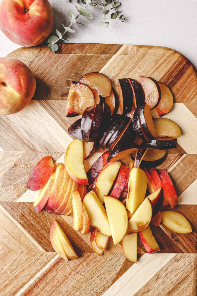 sliced peaches and plums on a cutting board