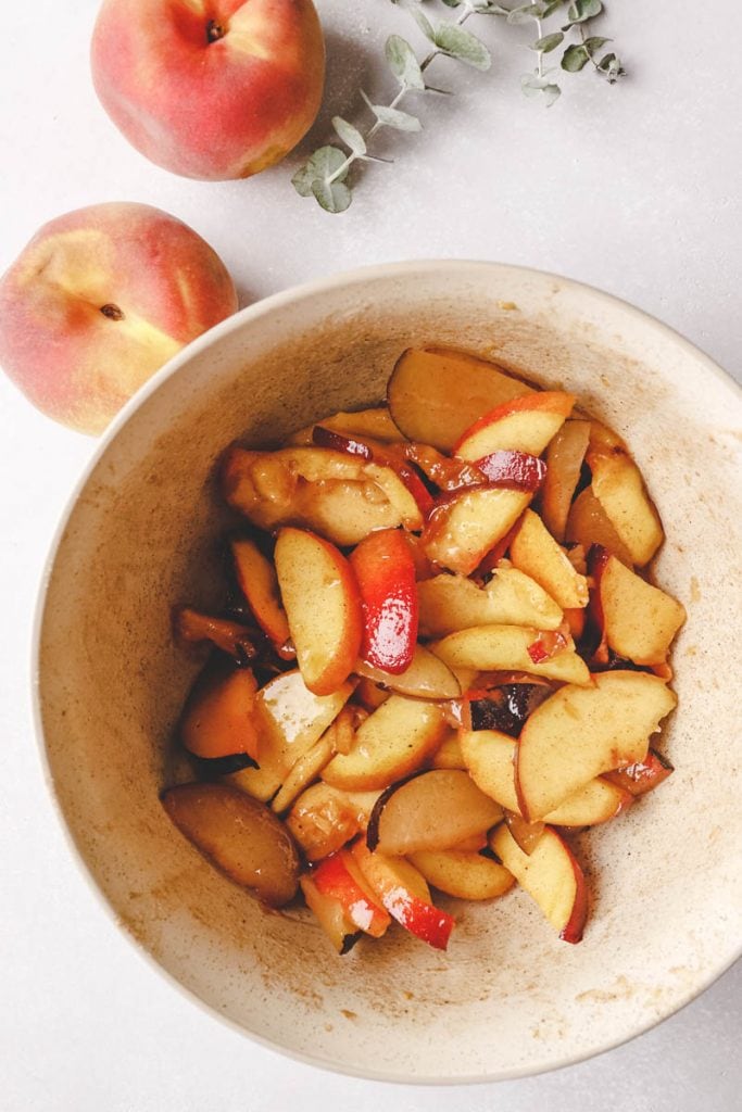 peaches in a bowl tossed with spices and sugar