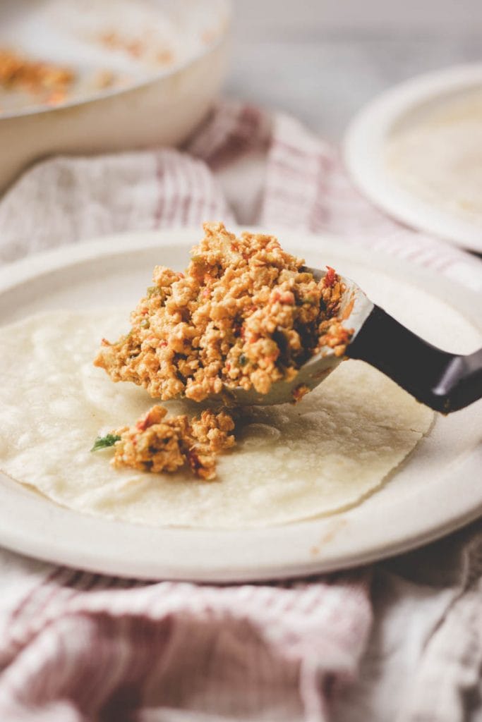 serving southwest tofu scramble into a tortilla