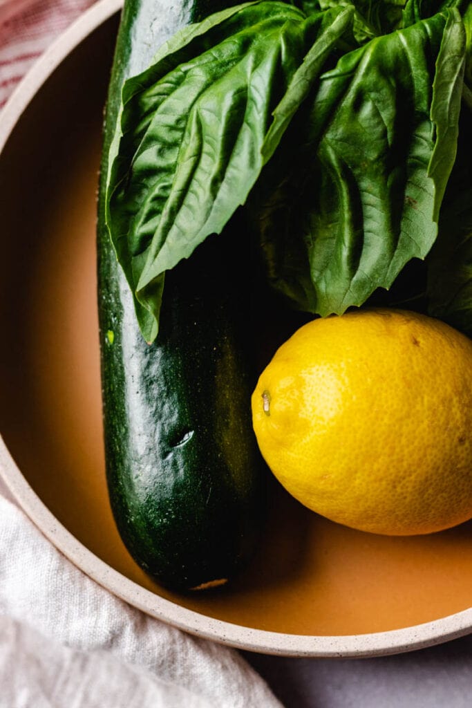 fresh zucchini, basil and a lemon in a bowl