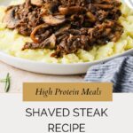 A plate of mashed potatoes topped with a savory shaved steak recipe and mushroom mixture, garnished with fresh rosemary, with text overlay: High Protein Meals: Shaved Steak Recipe with Rosemary.