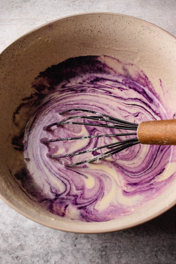 stirring in the ube extract into the waffle batter