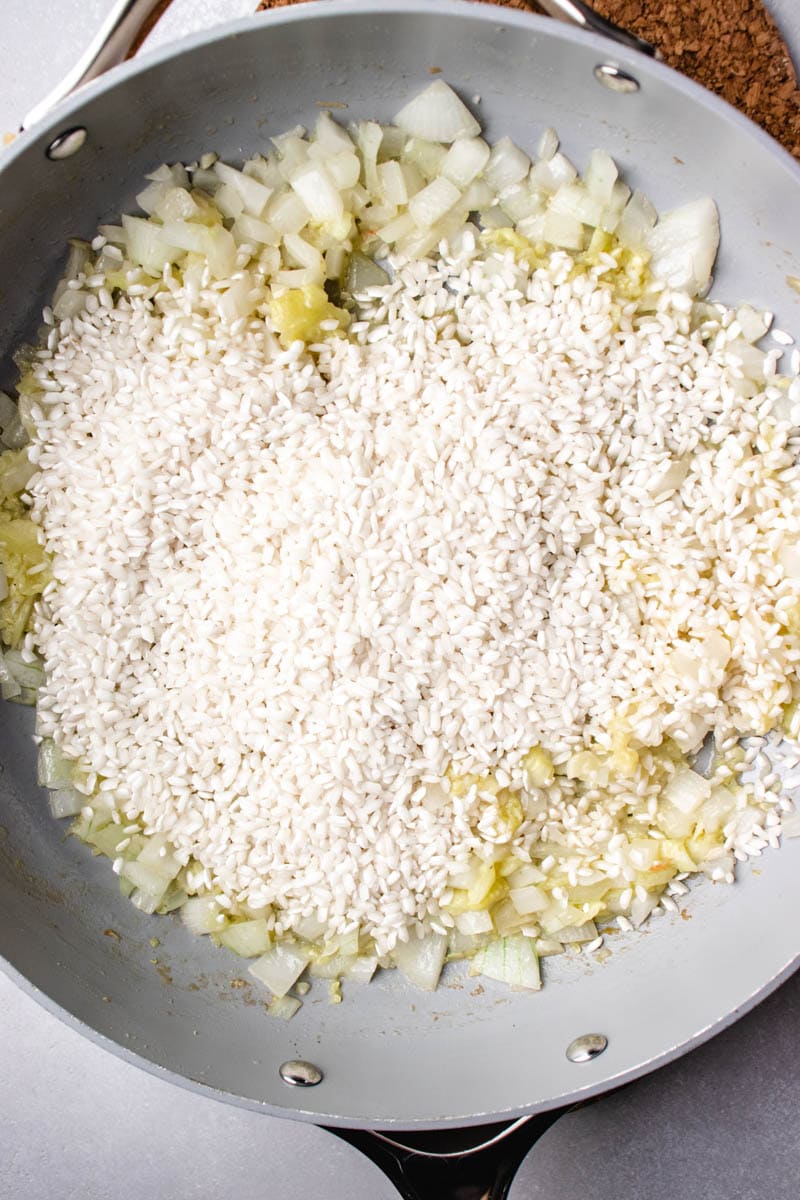A skillet filled with rice and onions.