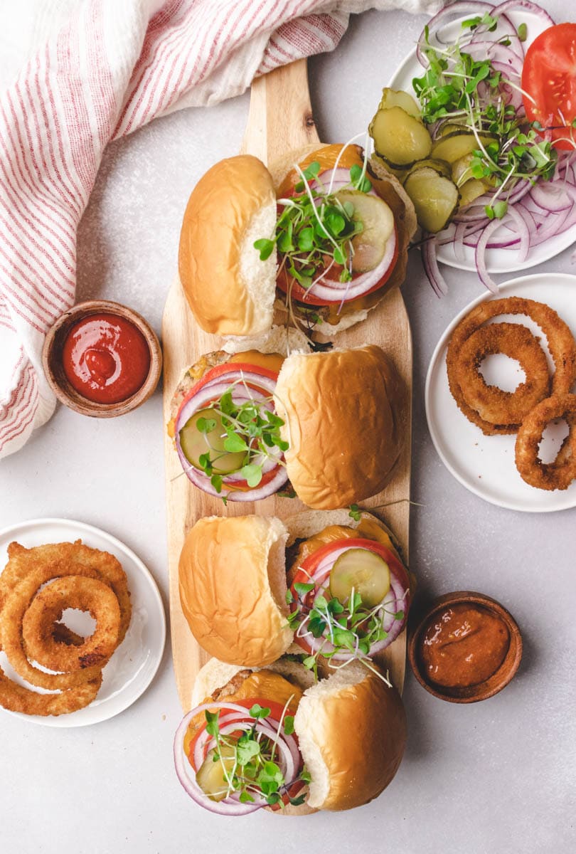 turkey basil burgers on a serving board with onion rings and ketchup