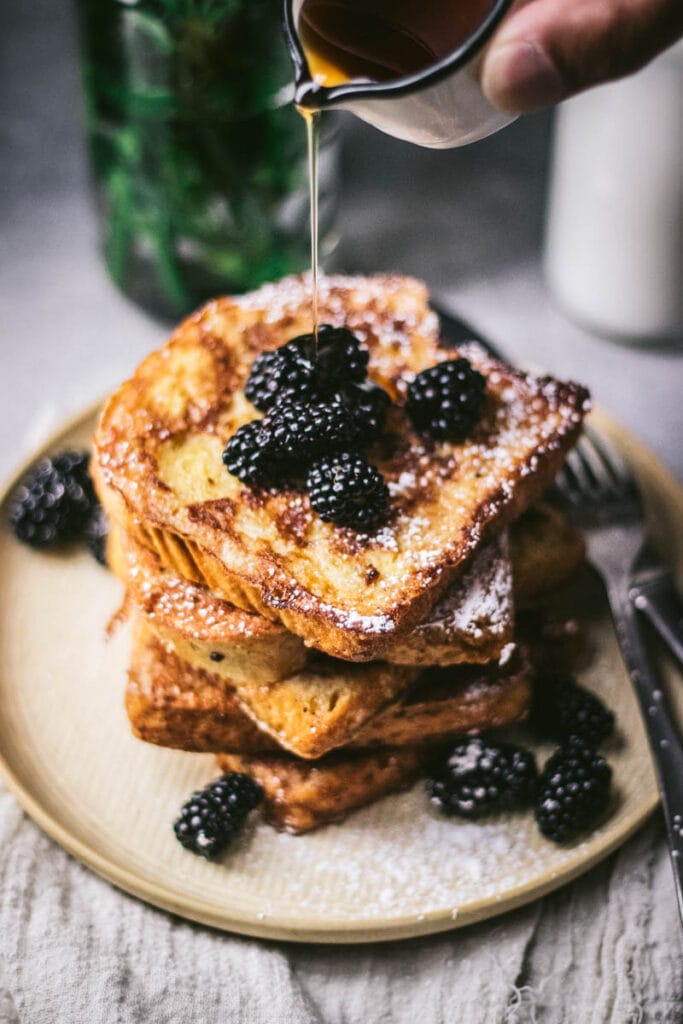 pouring maple syrup on top of french toast