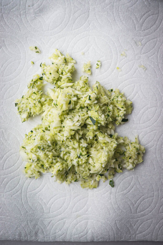 removing excess moisture from the zucchini with paper towels