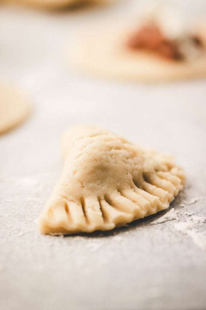 folding over the empanada into a half moon with the sealed edges