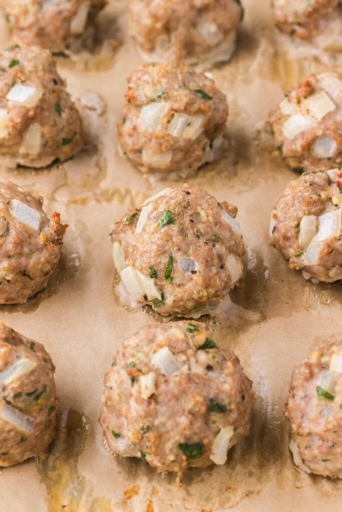 Gluten free meatballs on a sheet pan and parchment paper.