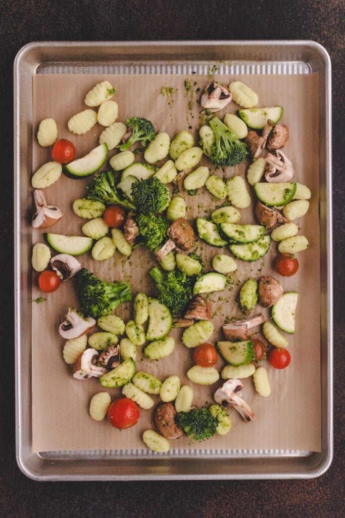 Process shot of gnocchi with pesto and vegetables. Gnocchi and veggies on a sheet pan.