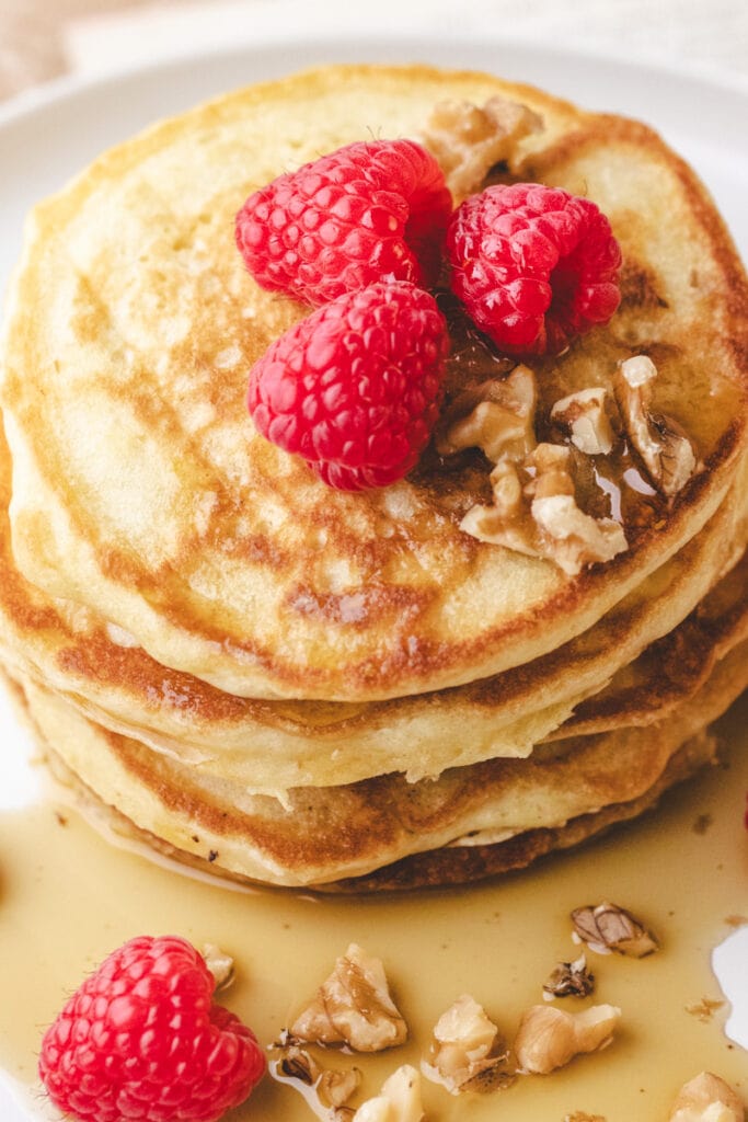 top of pancake stack with raspberries and syrup.