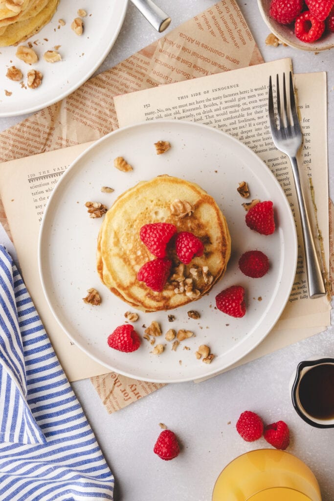 lemon raspberry pancakes on a white plate with a fork and napkin.