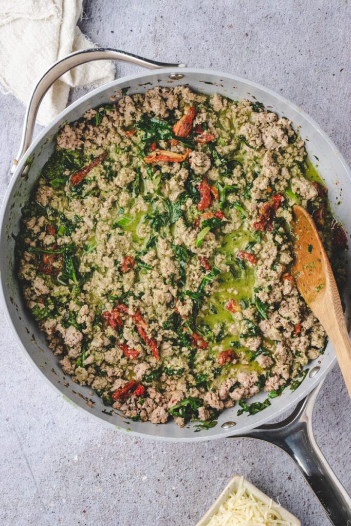 Ground turkey milk and chicken broth, sun dried tomatoes and pesto in a large pan.