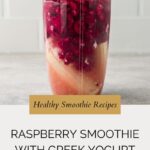 A clear blender cup filled with vibrant layers of raspberry smoothie with Greek yogurt sits on a gray surface. The text reads: “Healthy Smoothie Recipes. Raspberry Smoothie with Greek Yogurt. whensaltyandsweetunite.com”.