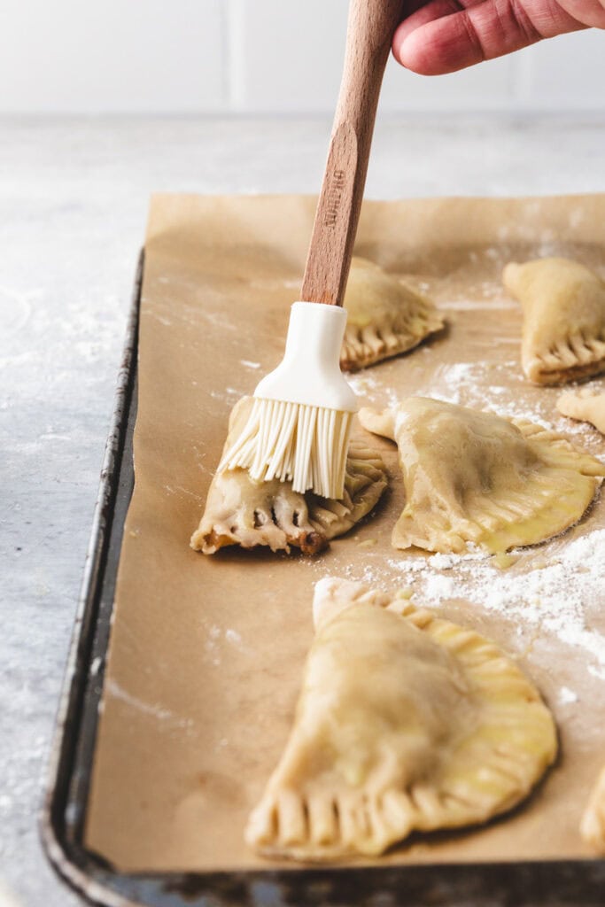 apple empanada being brushed with egg wash