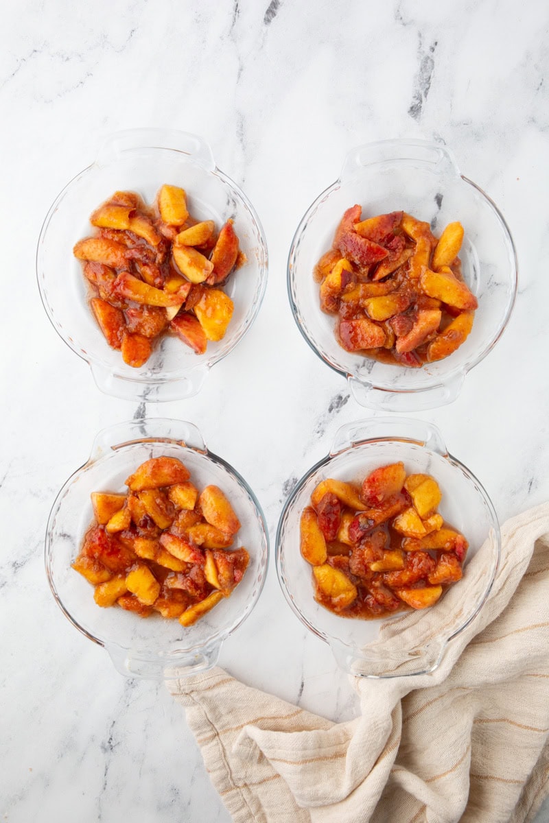 adding peaches to mini pie dishes.