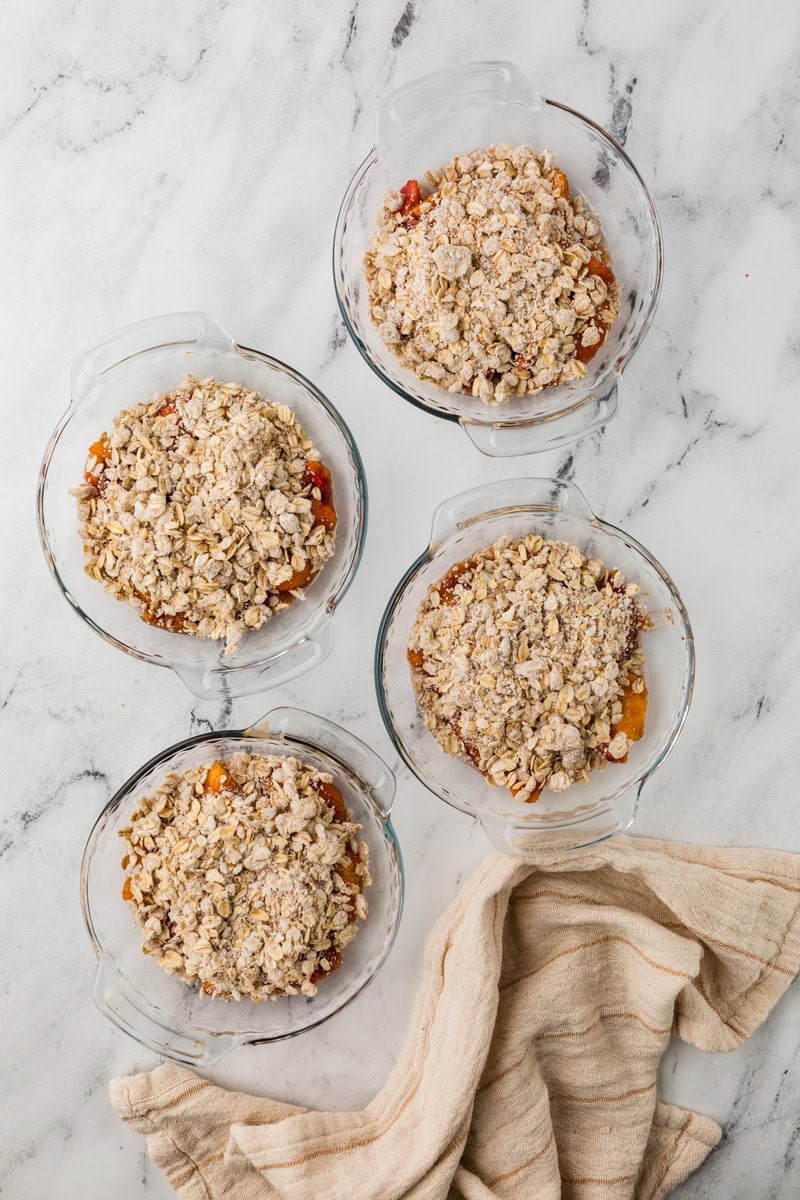 assembling peach crisps into pie dishes.