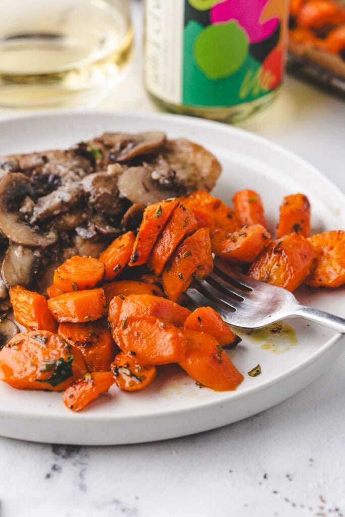close up shot of carrots on a fork on a white plate.