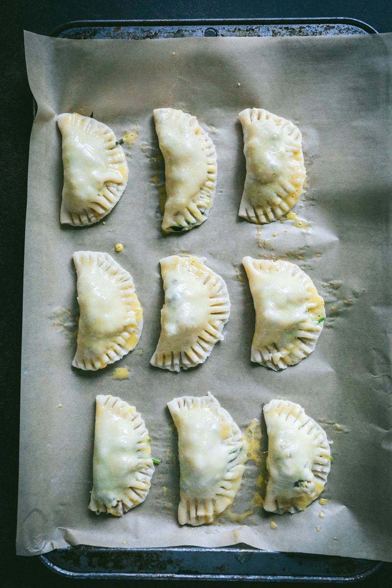 empanadas on a sheet pan with egg wash .