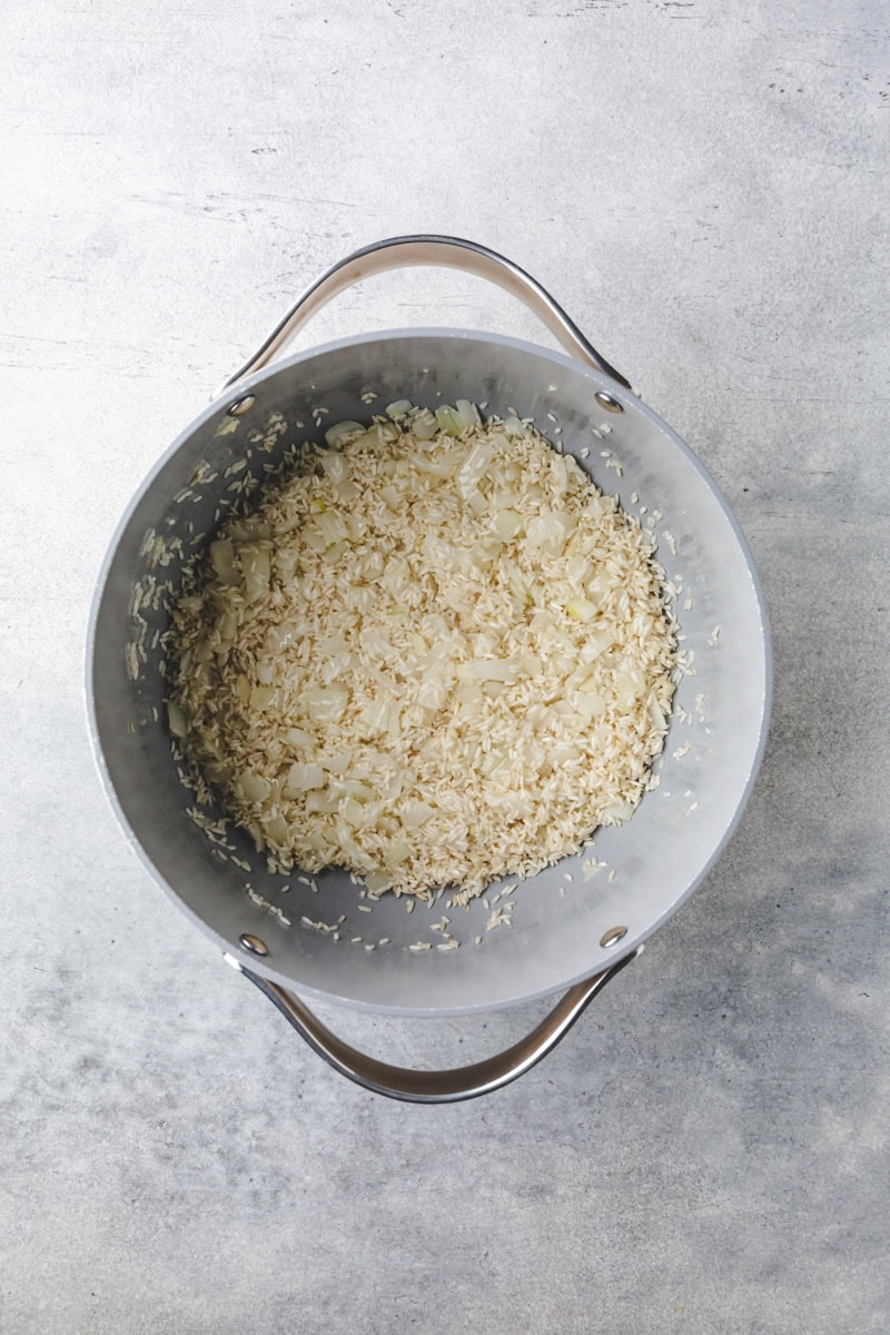 rice and onion sauteing in a pot.