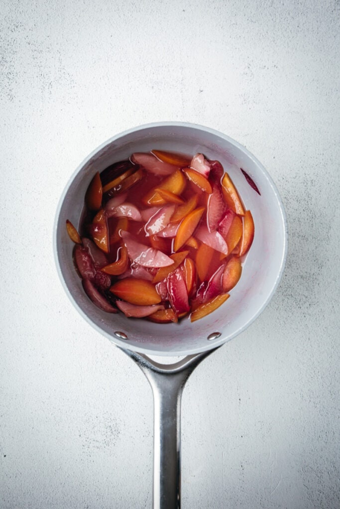 sliced fruits in a pan with sugar.