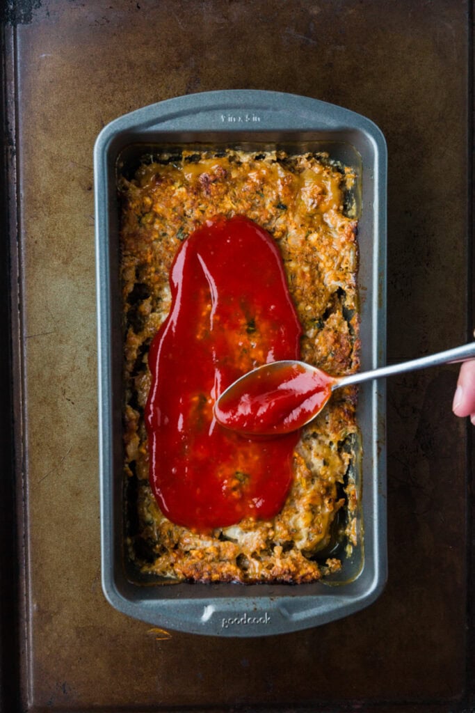 adding the ketchup glaze to the meatloaf.