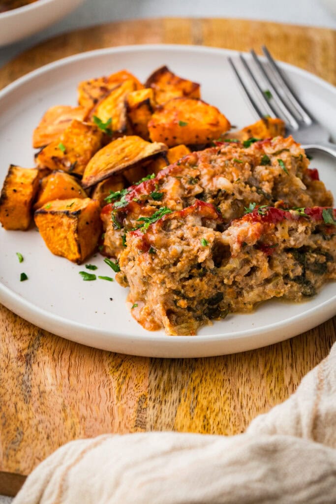 slice of turkey meatloaf on a plate with sweet potatoes.