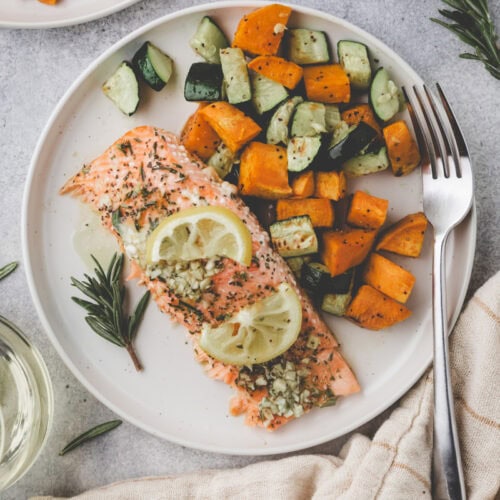 salmon with rosemary on a plate with vegetables.