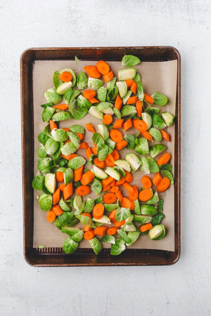 Chopped Brussels sprouts and carrot slices, perfect for Roasted Carrots and Brussels Sprouts, arranged on a parchment-lined baking sheet, ready for roasting.