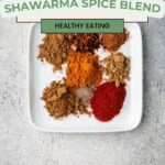 A white square plate displays an array of colorful spices, with brown, red, and orange hues, neatly arranged on a gray surface. Text above reads Easy and Simple Shawarma Spice Recipe and Healthy Eating.