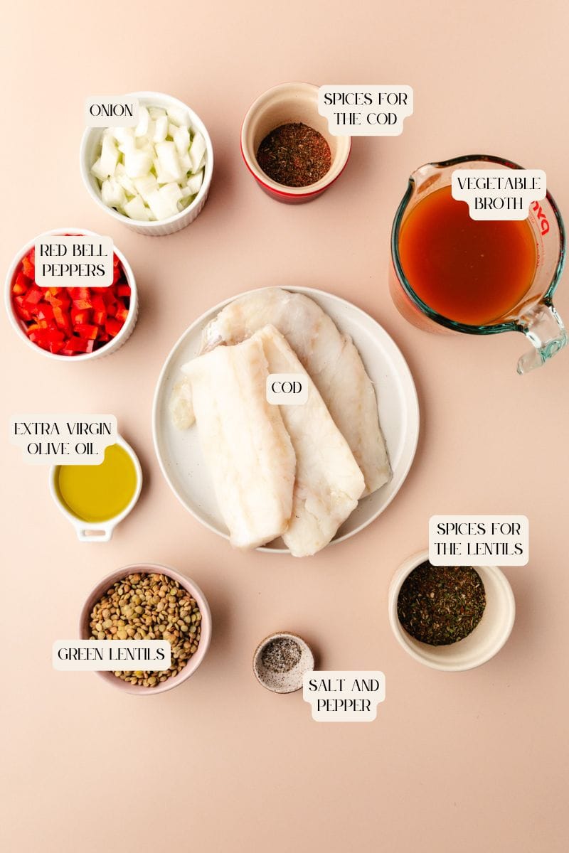 Ingredients arranged on a surface: raw cod fillets on a plate, chopped onion, red bell peppers, spices, fish and green lentils, salt and pepper, vegetable broth in a measuring cup, and a small dish of olive oil. Labels indicate each item.