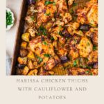 A sheet pan with roasted harissa chicken thighs, golden potatoes, and cauliflower, garnished with parsley, sits beside bowls of yellow rice and green herb sauce. Discover this flavorful harissa chicken recipe on our website.