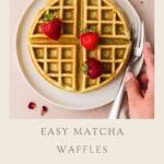 A plate with a matcha waffle topped with three strawberries, a fork and knife beside it, and a hand reaching for them. The text below reads: Easy Matcha Waffles Brunch Food Ideas whensaltyandsweetunite.com.