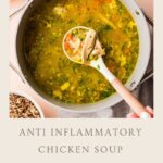 A pot of chicken soup filled with vegetables and herbs sits on a table. A ladle lifts chicken and broth from the pot. Ingredients like eggs, parsley, and grains are arranged nearby. Text reads: Anti Inflammatory Chicken Soup.