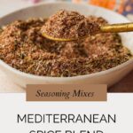 A spoonful of Mediterranean Spice Mix held above a bowl filled with the same seasoning, with colorful fabric in the background and text highlighting this flavorful Mediterranean spice blend recipe.