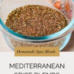 A glass bowl filled with Mediterranean Spice Mix sits on a light surface, with a colorful cloth in the background. Text reads “Homemade Spice Blends, Mediterranean Spice Blends.”.