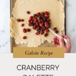 A hand spreads cranberry filling onto a sheet of dough on a parchment-lined tray. Text below reads Cranberry Galette Recipe: How to make the perfect cranberry galette, with a website link included.