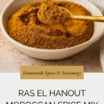 A bowl filled with Ras El Hanout Moroccan spice mix sits on a beige surface, with a gold spoon resting inside. Text below reads Homemade Spices & Seasonings: Ras El Hanout Moroccan Spice Mix.