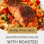 A blackened salmon fillet sits atop a colorful quinoa salad with roasted vegetables on a white plate. Text overlay reads: Healthy Winter Meals: Salmon Quinoa Salad with Roasted Veggies.