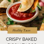 A hand dips a crispy baked taco into a bowl of red salsa. Other tacos and fresh cilantro are on a brown surface. Text below reads, “Healthy Tacos. Crispy Baked Bison Tacos. whensaltyandsweetunite.com.”.