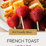 A plate of food featuring french toast kebabs with strawberries and cubes.