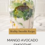 A blender cup filled with spinach, avocado, mango, chia seeds, a drizzle of oil, and milk sits on a marble counter, with text highlighting a refreshing mango avocado smoothie recipe.