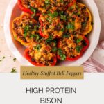 A white plate of bison stuffed peppers filled with melted cheese and herbs sits on a light table. Text reads: Healthy Stuffed Bell Peppers. High Protein Bison Stuffed Peppers. when saltyandsweetunite.com.