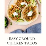 A plate of three ground chicken tacos on corn tortillas, topped with chickpeas, cilantro, and sour cream, served with lime wedges. A bowl of extra sour cream sits nearby, highlighting the fresh flavors of these ground chicken tacos.