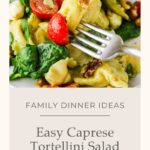 A fork holds a bite of tortellini, spinach, and cherry tomato above a plate of Caprese Tortellini Pasta Salad with greens and walnuts. Text reads: Family Dinner Ideas. Easy Caprese Tortellini Salad. whensaltyandsweetunite.com.